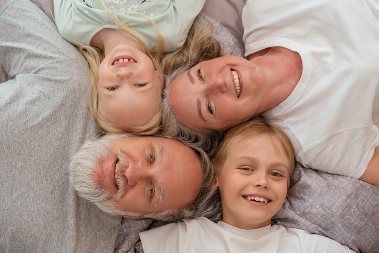 A joyful multigenerational family lying down and smiling together, displaying warmth and affection.